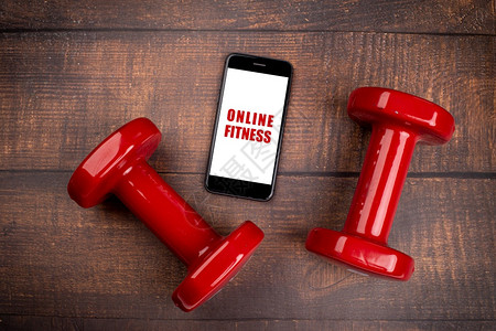 为了奏鸣曲用于培训室内在线健身方案的红哑铃和智能手机木林背景App用于培训室内在线健身方案家庭在线锻炼TopViewCovid1图片