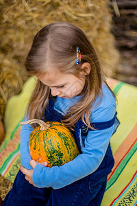 感恩白种人与黄熟南瓜和背景的有趣孩子在大草背景与南瓜的有趣孩子萝卜图片