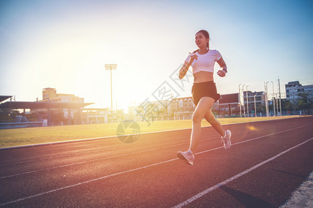 轮廓亚裔年青健身女运动员在体育场赛道上奔跑年轻的红色图片