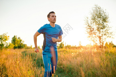 运动健壮的青年男子在公园户外跑动晚上夕阳光在公园户外跑动健康生活方式身概念体育青年男子在公园户外运动肌肉按图片