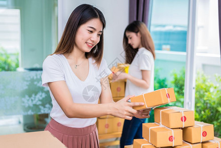航运女士两名年轻的亚洲女孩自由职业青年商所有者在家庭办公室工作分拣包裹邮箱为客户包装订单和网上购物概念提供送货服务Scheppi图片