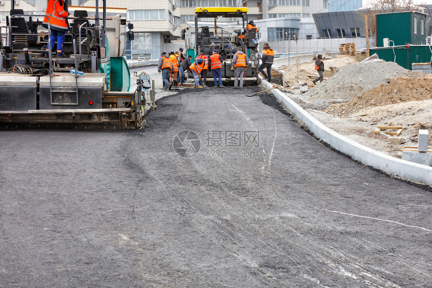 道路团队正在与两个工业摊铺机合作将第一层热沥青铺在新的一段道路上复制空间两个工业摊铺机将第一层热沥青铺在新的一段道路上劳工碎石铺图片