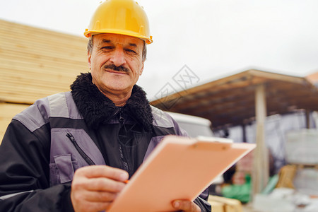 Caucasian高级男子建筑工一般人建筑承包商的肖像他们身着黄色保护头盔手持钢笔和现场数据报告项目文件核对检查档控制高级的图片
