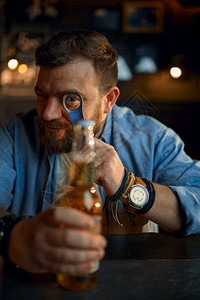 职业坐着瓶子快乐的男人拿着一瓶啤酒坐在吧的柜台一个男人在酒吧里类的情感休闲活动夜生拿着一瓶啤酒的男人坐在吧柜台图片