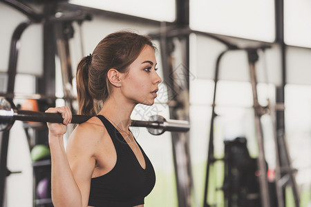 健身房举杠铃锻炼的年轻女子图片