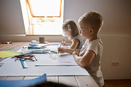 两个孩子在桌上用铅笔和记号画孩子们在工作室里艺术学校上课年轻画家愉快的爱好乐童年两个孩子用铅笔和记号画桌子女创造力图片