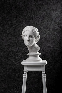 极简主义时代黑色纹理椅子上的古代白色维纳斯半身像石膏复制品雕塑女人脸希腊神话中的爱情女文艺复兴时期古代白色半身像维纳斯雕的石膏复图片