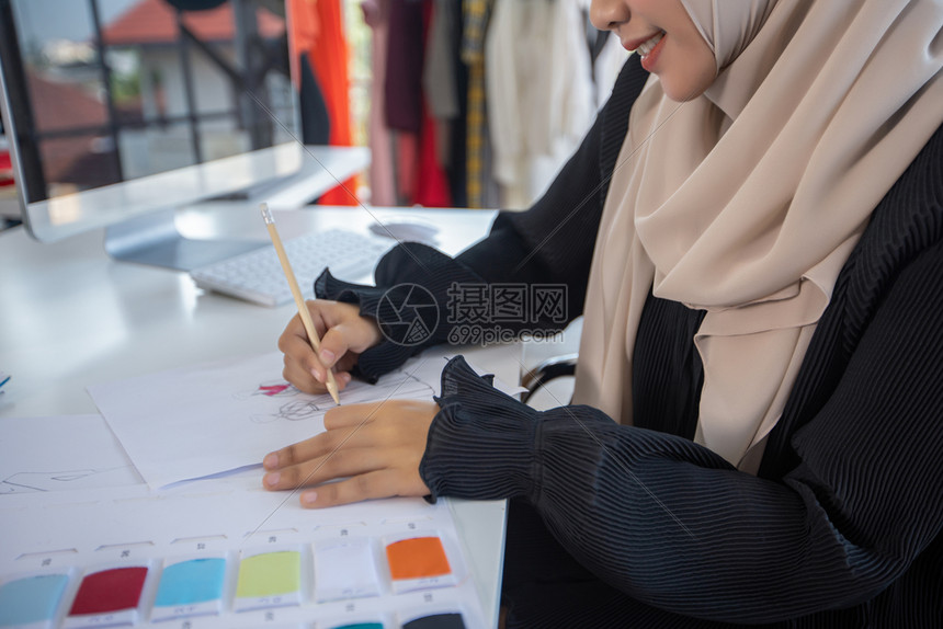 时髦的妇女时装设计师的小企业在服装店工作并使用智能电话和与一起使用的平板电脑精品店织物图片