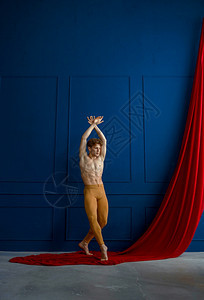 古典灵活男芭蕾舞者在蹈班蓝色墙壁和背景布上穿红色衣服的男子芭蕾舞者在蹈班有肌肉身材优雅和运动的表演者中姿势模型图片