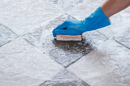 戴蓝橡胶手套的男子掌用来转换瓷砖地板上的洗涤工作卫生建造女佣图片