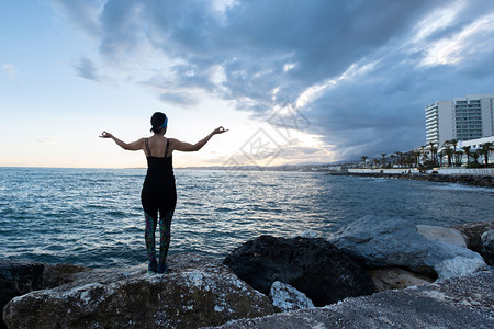 关心摆姿势运动女人在阴云的一天海滩上做瑜伽图片