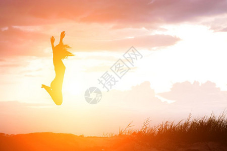 快乐的女子在美丽日落面前跳跃轮廓健康女士图片