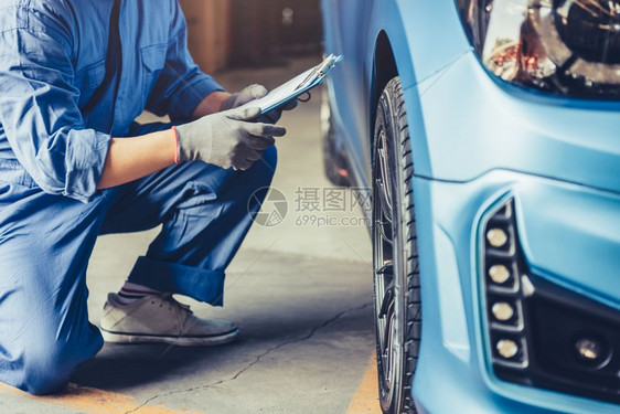 亚洲汽车机械技工术员持有剪贴板并在汽车修理间轮胎修理服务中通过客户索偿单对维修车辆进行检查手持剪贴板和保养车辆的亚洲汽机械技工保图片