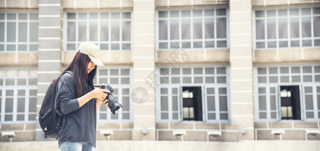 亚洲人旅游者使用dslr专业摄影机在度假旅行时使用Dslr专业照相机的亚洲旅游者年轻女旅行者携带背包和照相机前往老城美丽的女士背图片