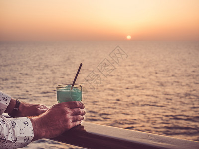 在海浪的背景下在游轮露天甲板上戴着鸡尾酒的手和美丽玻璃杯侧观休闲与旅行特切概念以及带鸡尾酒的Manrrrqopos手和玻璃酒吧冰图片