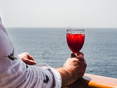 波浪粉色的日落在海浪背景下在游轮露天甲板上戴着鸡尾酒的手和美丽玻璃杯侧观休闲与旅行特切概念以及带鸡尾酒的Manrrrqopos手图片