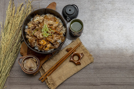 日本猪肉饭碗配鸡蛋和洋葱Donburi在木桌日本菜风格上配有姜咸菜和绿茶日本人煮熟的送达图片