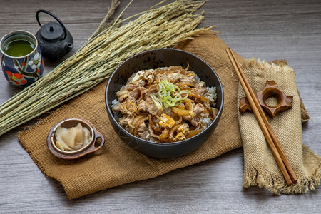 日本猪肉饭碗配鸡蛋和洋葱Donburi在木桌日本菜风格上配有姜咸菜和绿茶美味的食物丽图片
