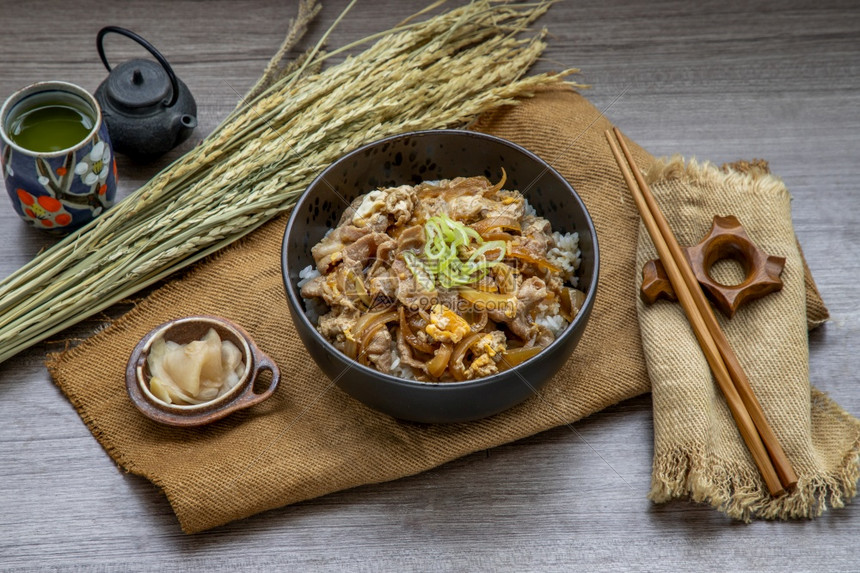 日本猪肉饭碗配鸡蛋和洋葱Donburi在木桌日本菜风格上配有姜咸菜和绿茶美味的食物丽图片