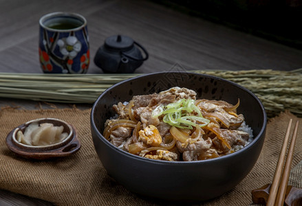 吃日本猪肉饭碗配鸡蛋和洋葱Donburi在木桌日本菜风格上配有姜咸菜和绿茶亚洲筷子图片