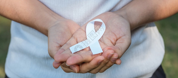 手握白色丝带预防癌症概念背景图片