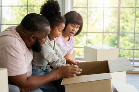 母亲混合种族家庭坐在沙发上搬家后第一天从邻居处打开礼物箱后感到惊讶概念为新家庭开始的生活概念为新家庭开始的生活孩子们盒图片