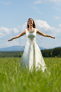 年轻的可爱花穿着结婚礼服的女孩在他臂膀飞行场背景图片