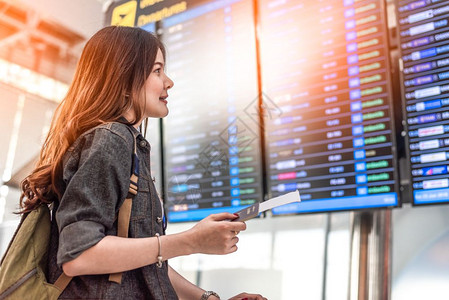 离开观察飞行时间的亚洲美容女旅游者在检查飞行时间表可以抽出间人与生活方式概念单身女主题的旅行与快乐生活BackView肖像手提箱图片