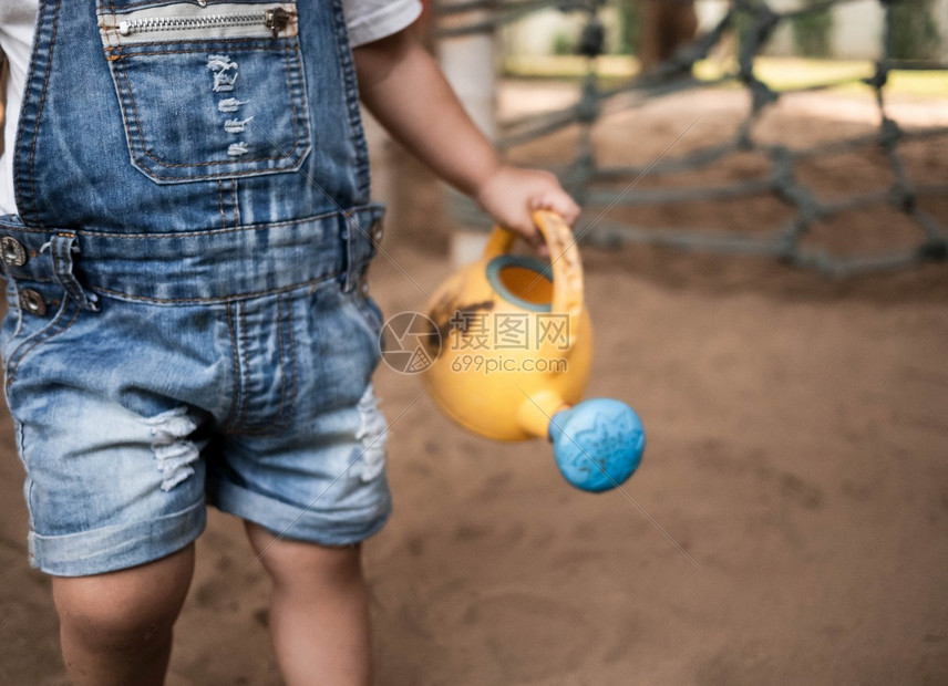 角色健康户外紧贴的亚裔小女孩拿着塑料水在操场玩具用塑料沙滩玩具打子乐于游戏为儿童学习笑声图片