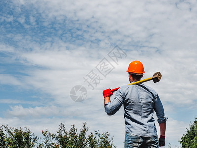 在绿树的背景下在公园中持有大锤的吸引力男人关闭劳动和就业概念在公园中持有大锤的吸引力人c关闭劳动力和就业概念春天快乐的夏图片