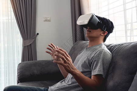 观看增强型瘾君子一个快乐的男人坐在沙发上戴着3D虚拟真人眼镜图片