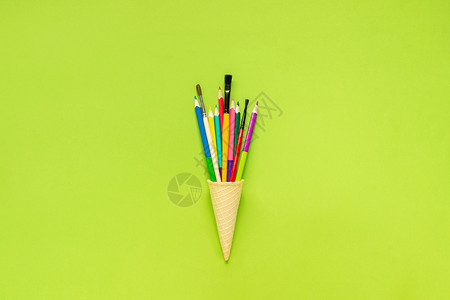 最佳平坦的知识彩色铅笔在绿纸背景的华夫冰淇淋甜锥中漆刷绿色纸背景的概念教育或回到学校平板版明信片字母文本或设计最优视图模板花纸面图片