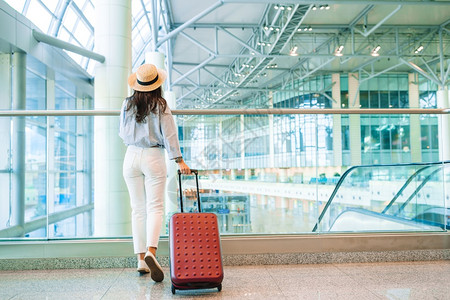 在国际机场带行李的年轻女子带着行李在机场休息室等待飞机的航空公司乘客班冒险车站图片