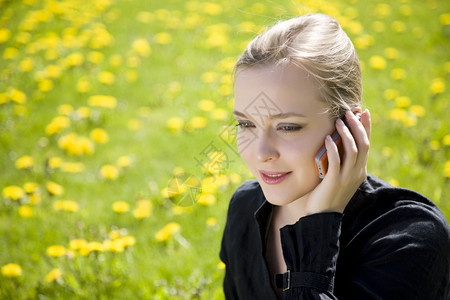 脸请讲年轻女通过电话在草地上发言讨论图片