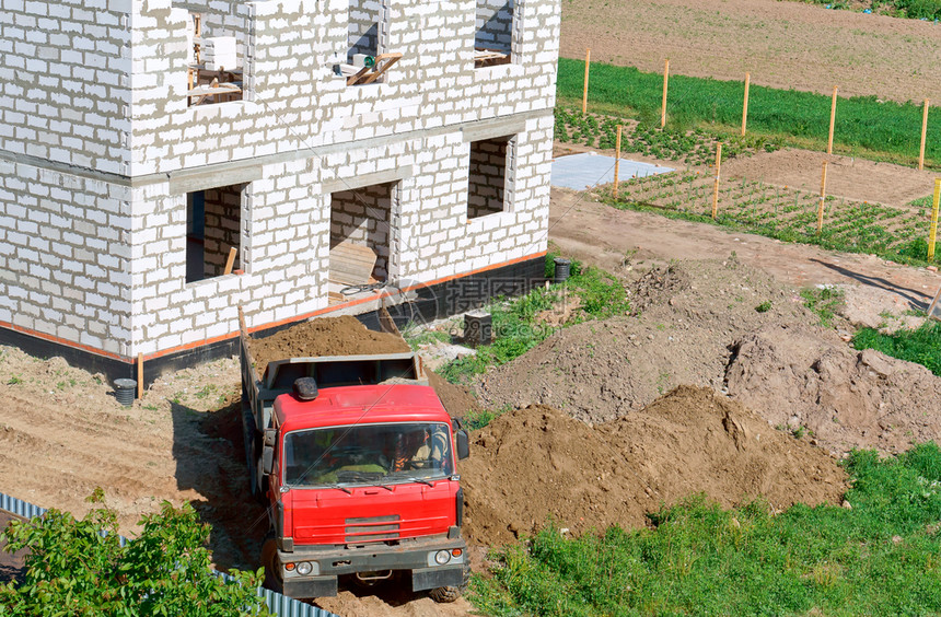 俄罗斯一种辆卡车和栋用白砖制成的建筑物垃圾车将沙子带到建筑工地这是在建房屋附近的一辆倾卸卡车地点图片