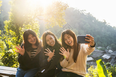 观光三位亚裔幸福女使用智能手机自拍在泰王国北部的地貌上旅行取用Vlog社会网络旅游及友情概念利用智能手机共拍自友谊图片