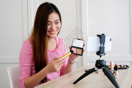 年轻女美容博客展示如何在用智能手机录音的同时补制视频辅导课程相机记录审查图片