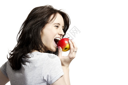 成人青春女在红苹果里咬着年轻快乐的女士吃着红苹果斯塔克有机的图片