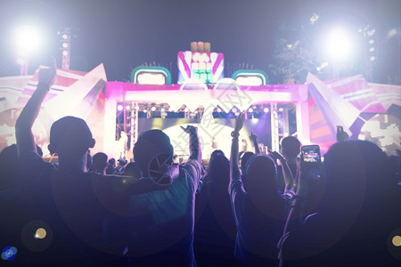 后五狂欢节抽烟音乐会群众在节日观看后举手向明亮的舞台灯升起迪斯科俱乐部背景