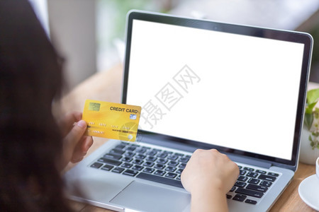 手持信用卡零笔记本电脑工作像背景一样在咖啡店用空白屏的笔记本电脑做工网上付费购物Onlinepayshopping白色的安全潮人图片