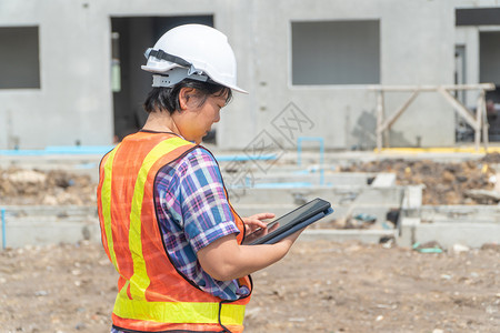 经理职业地点亚洲妇女工程公司持有一块平板用于检查建筑工地的准确并符合男女平等概念计划亚洲妇女工程公司拥有一张平板供根据男女平等概背景