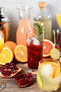 在柑橘水果和饮料的桌上加玫瑰和石榴的金鸡尾酒杜松子朗姆柚图片