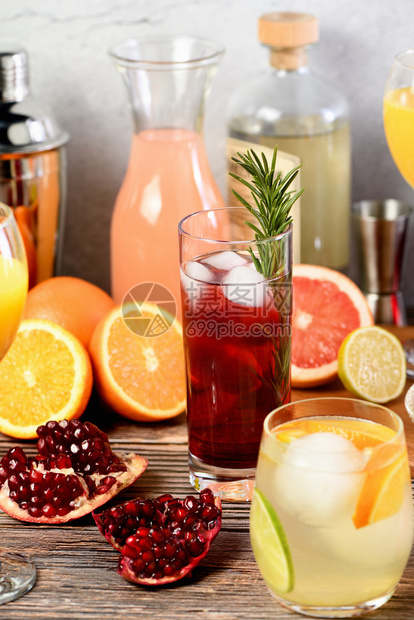 在柑橘水果和饮料的桌上加玫瑰和石榴的金鸡尾酒杜松子朗姆柚图片