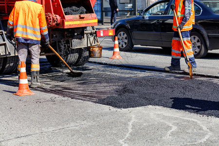 乌克兰活动建筑工人道路小组用新的沥青更部分道路用铲子修复一小段道路带有复制空间的图像道路工人小组正在用新鲜的沥青修复一段车道图片