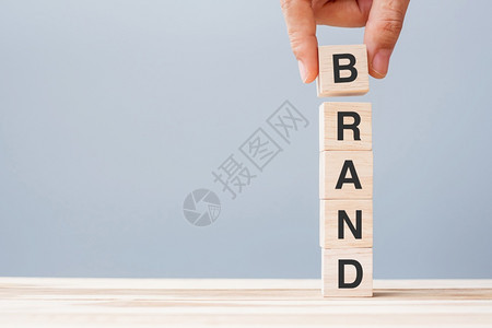 分配网络空间商人手握木制立方块布兰德公司在表背景营销广告和产品开发概念上写有BRAND公司字战略图片