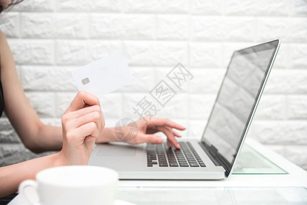 金融卡片妇女使用笔记本电脑商业和支付概念电子商务和互联网安全概念手持信用卡进行在线购物或从互联网订购产品并放松住家办公室的空间和图片