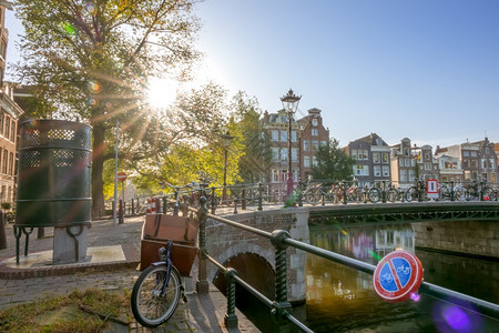 荷兰阿姆斯特丹Sunny上午在阿姆斯特丹传统住宅中许多自行车在离桥墙围栏附近的运河上位于阿姆斯特丹的Bridge街男厕所Sunn图片