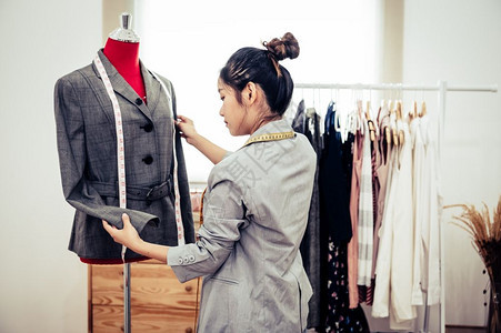 织物测量正式的亚洲女时装设计师亚洲女时装设计师穿着模特服装穿正式西的制服时设计师表演室缝衣和裁概念图片