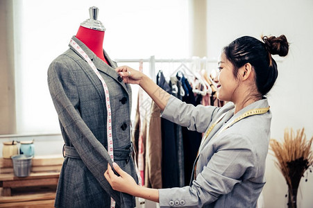 技能亚洲女时装设计师亚洲女时装设计师穿着模特服装穿正式西的制服时设计师表演室缝衣和裁概念纺织品措施图片