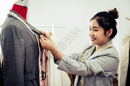 亚洲女时装设计师亚洲女时装设计师穿着模特服装穿正式西的制服时设计师表演室缝衣和裁概念造型师纫亚洲人图片